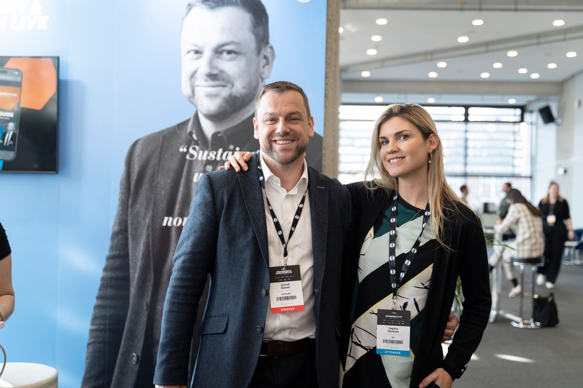 A man and a woman are posing for a picture in front of a man 's portrait.