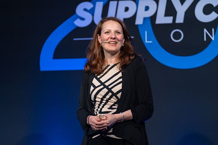 A woman is standing in front of a sign that says supply chain