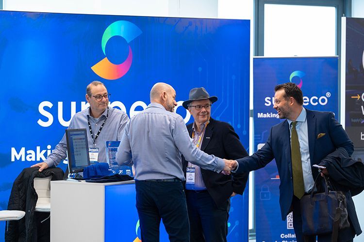 A group of men are shaking hands in front of a blue sign.