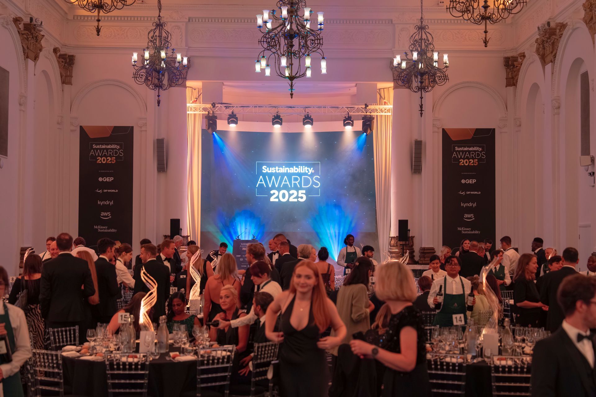 Guests gather in an elegant ballroom for the Sustainability Awards 2025, featuring grand chandeliers and a lit stage.