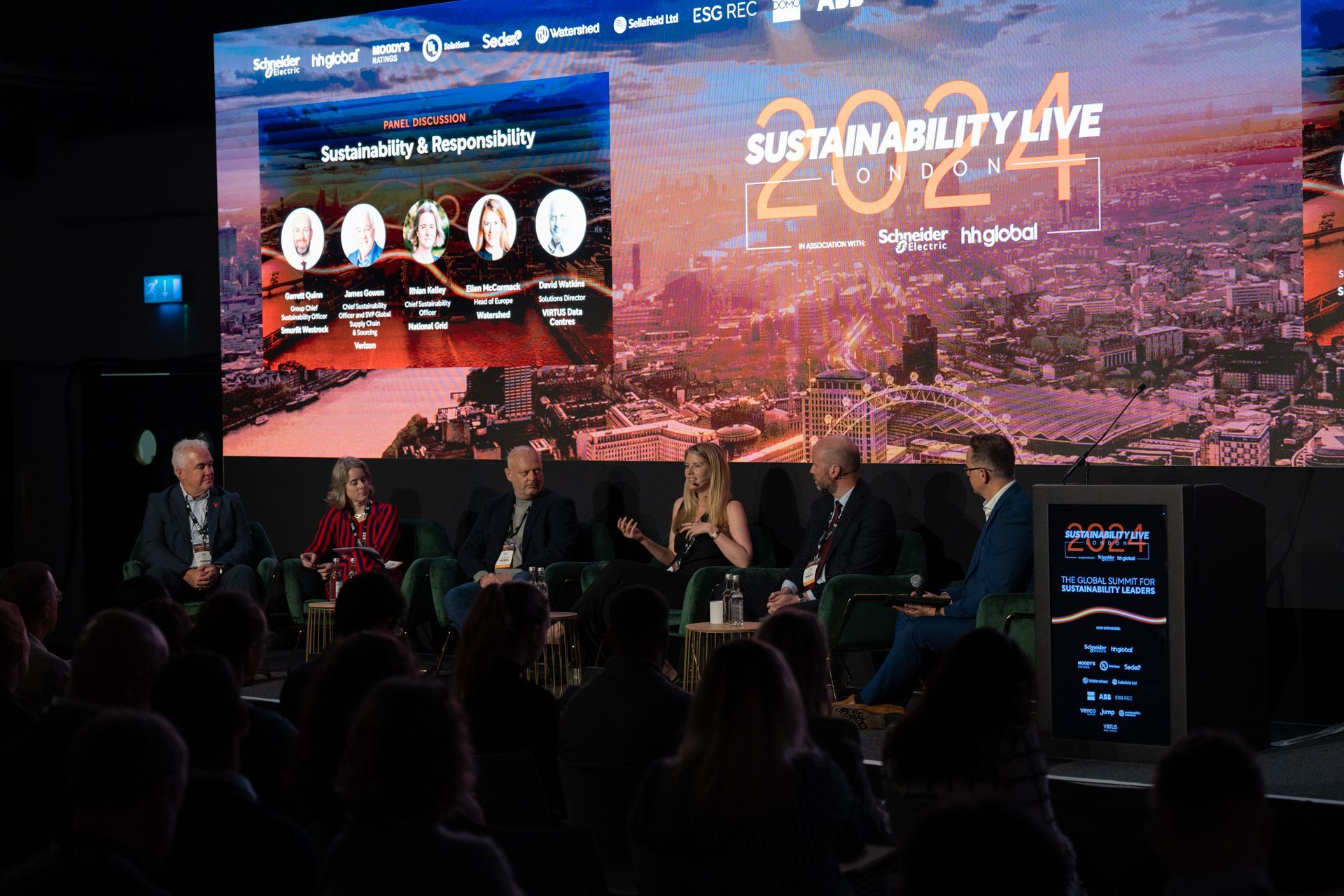 A group of people are sitting in front of a large screen.