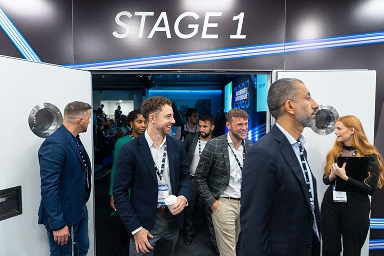 A group of people are standing in a room with a sign that says stage 1.