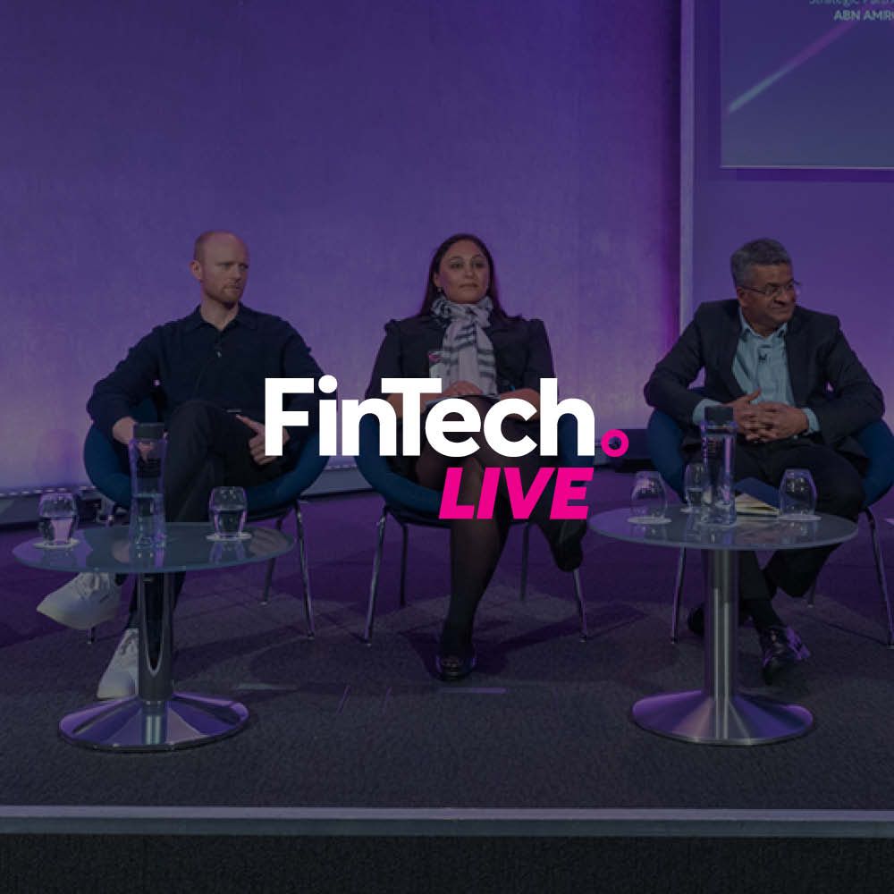 A group of people are sitting at tables in front of a purple background.