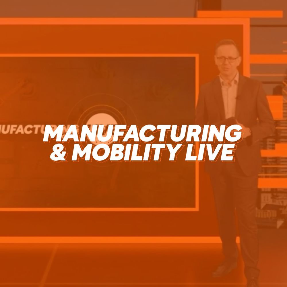 A man in a suit is standing in front of a screen that says manufacturing & mobility live