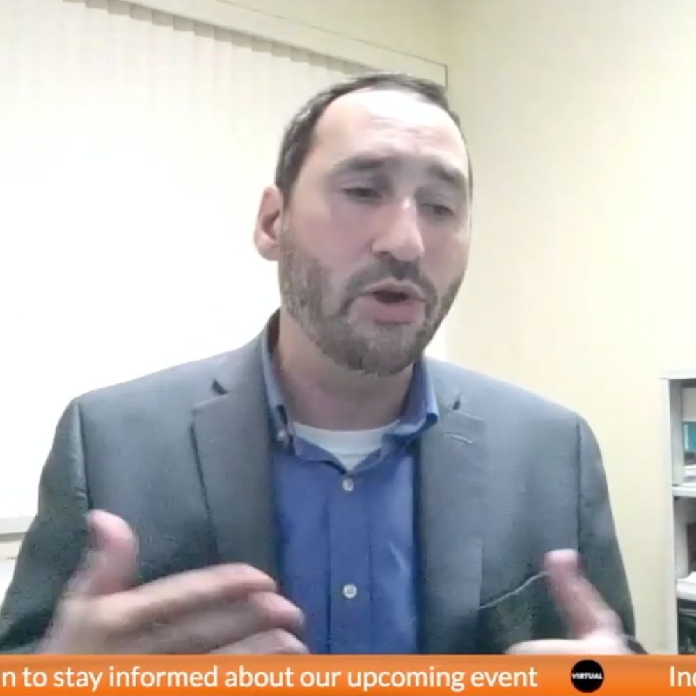 A man in a suit and blue shirt is talking on a video call