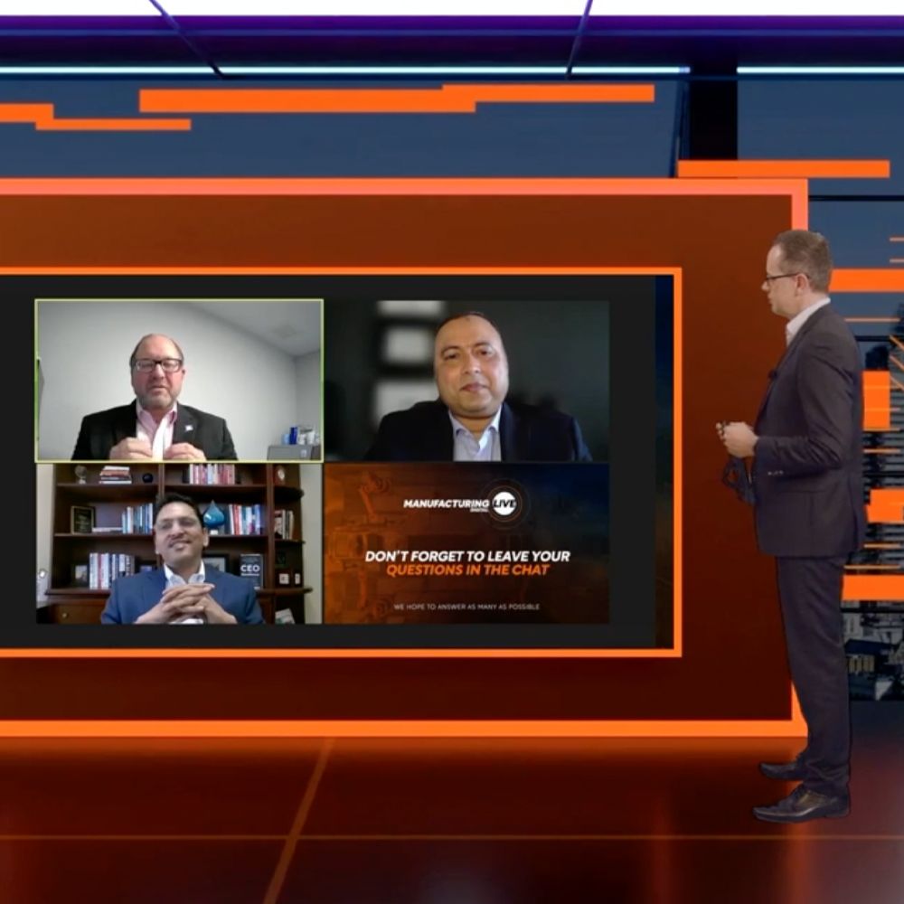 A man in a suit stands in front of a screen that says do n't forget to leave your questions in the chat