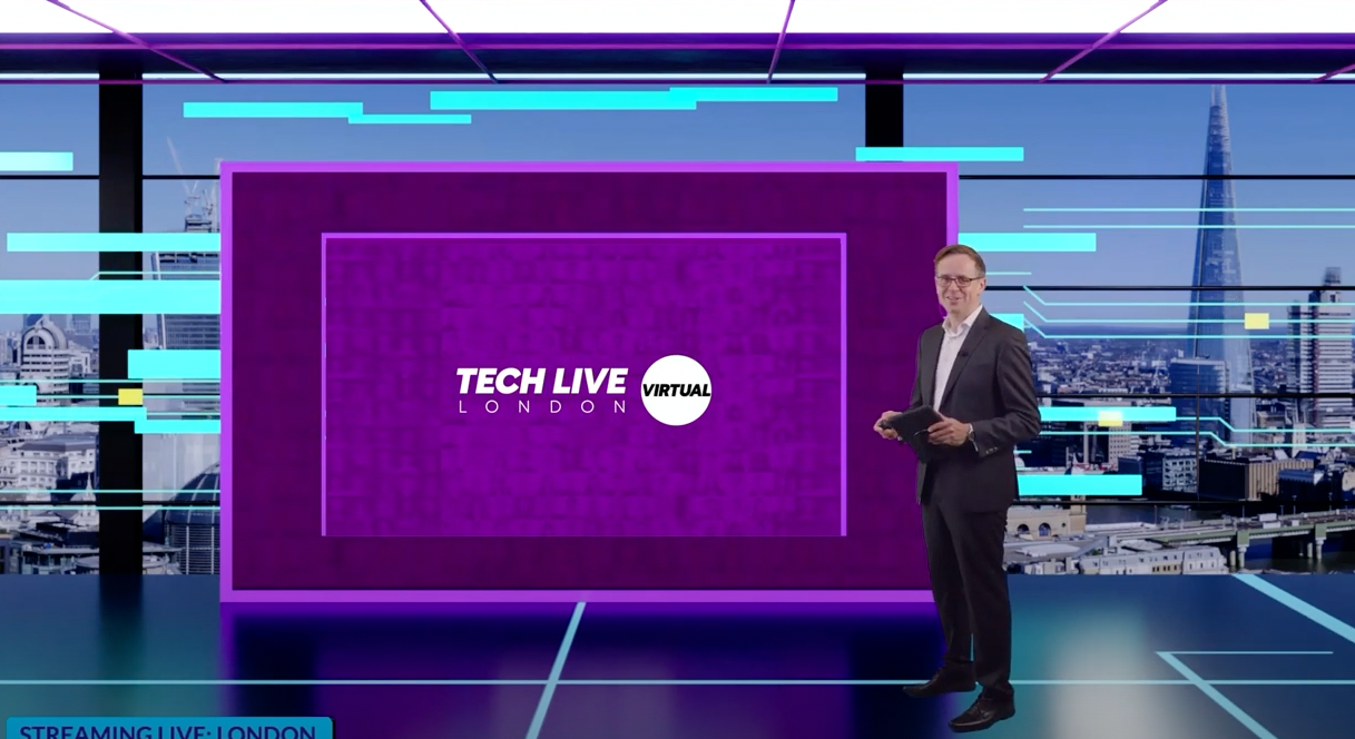 A man is standing in front of a screen that says tech live