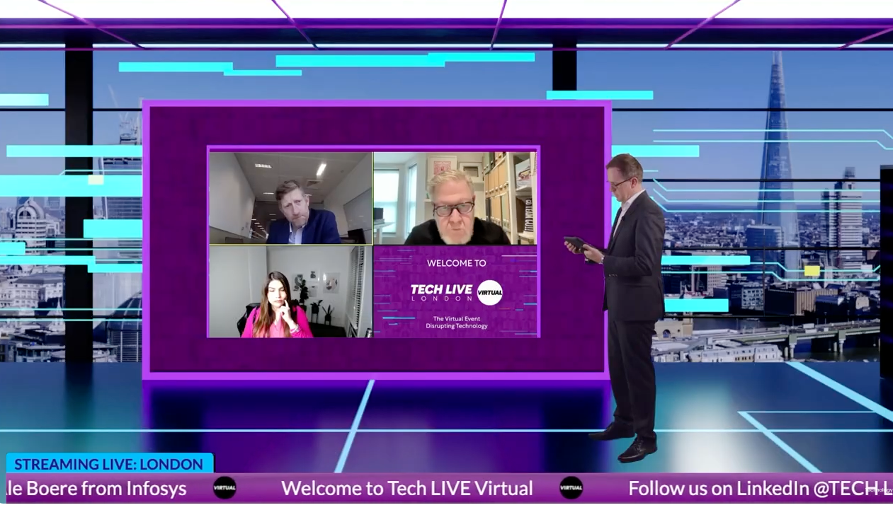 A man in a suit and tie is standing in front of a screen with three people on it.