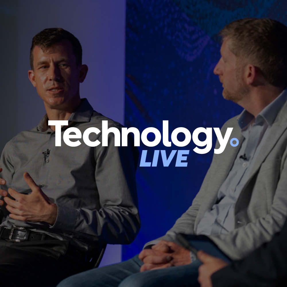 A group of men are sitting in front of a red background with the words tech & ai live on it.