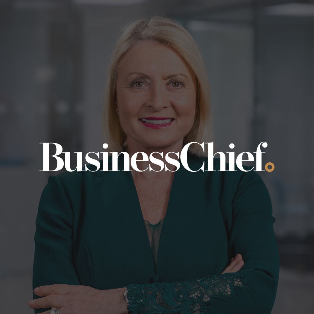 A woman is standing in front of a business chief logo.