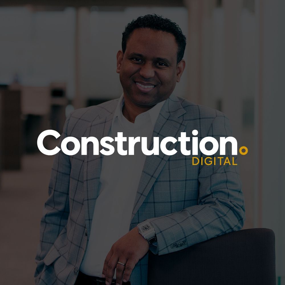 A man in a suit is standing in front of a construction digital logo.