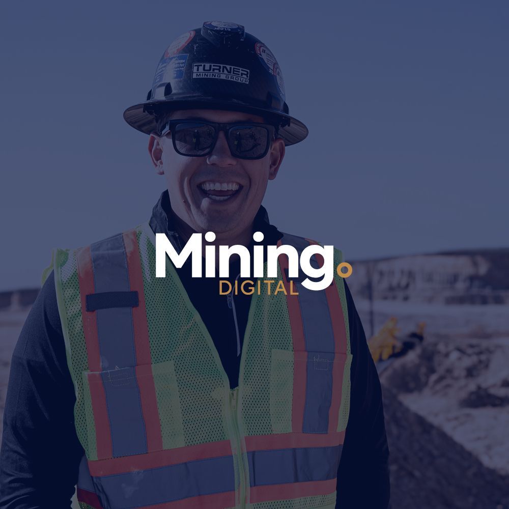 A man wearing a hard hat and sunglasses is standing in front of a sign that says mining digital.