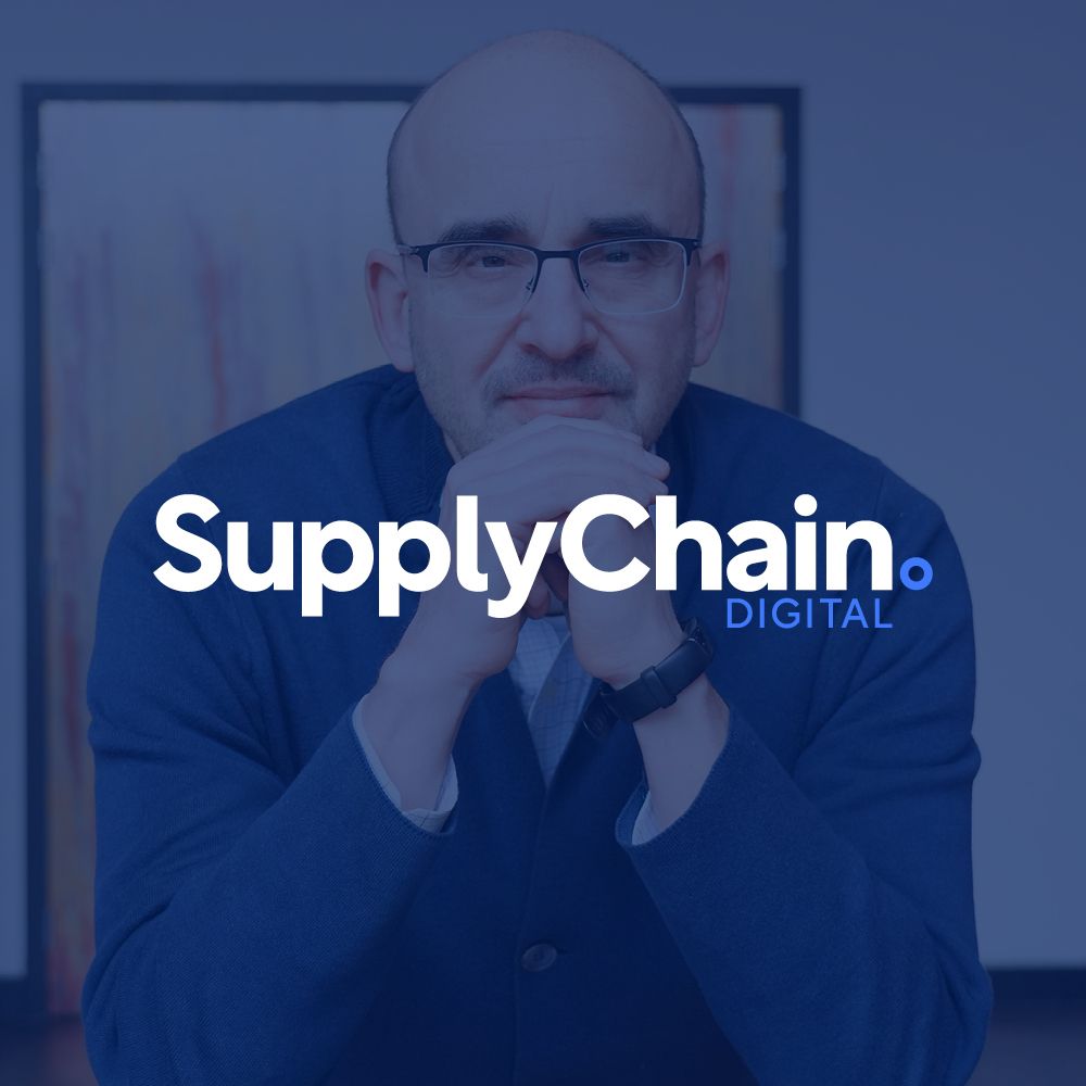 A man with glasses is sitting in front of a supply chain digital logo