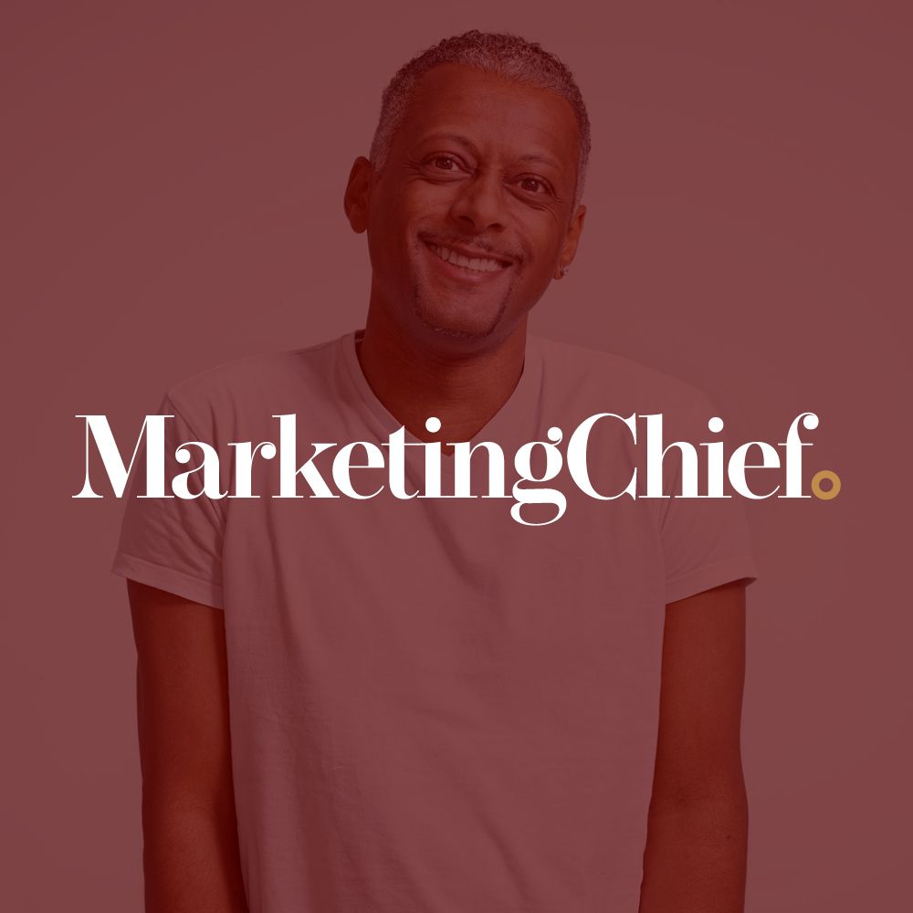 A man is smiling in front of a marketing chief logo