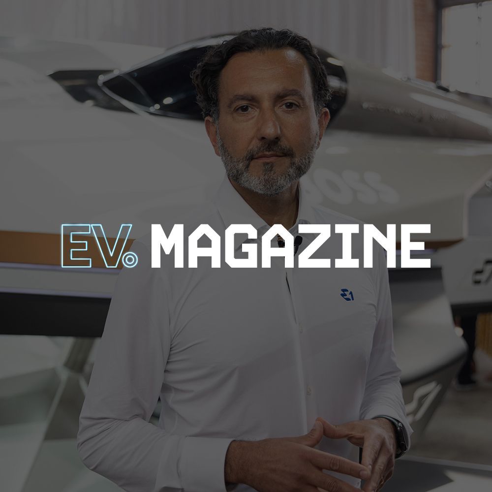 A man in a white shirt is standing in front of a plane and the ev magazine logo.