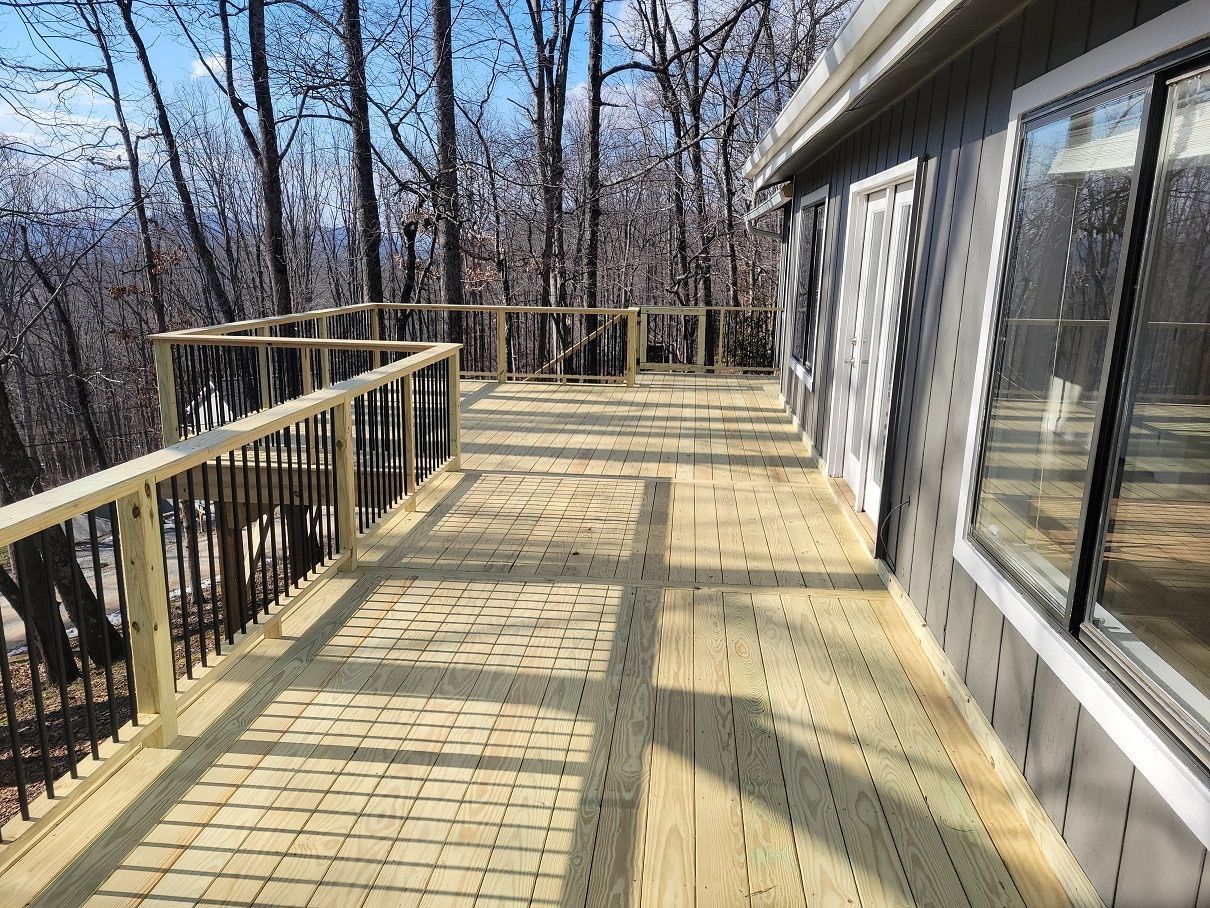 A wooden deck with a railing and trees in the background