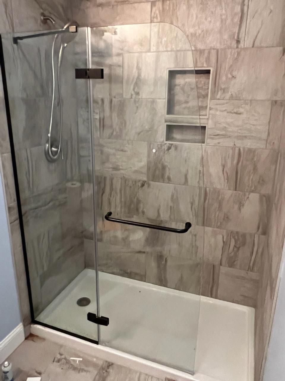 A bathroom with a walk in shower with a glass door.