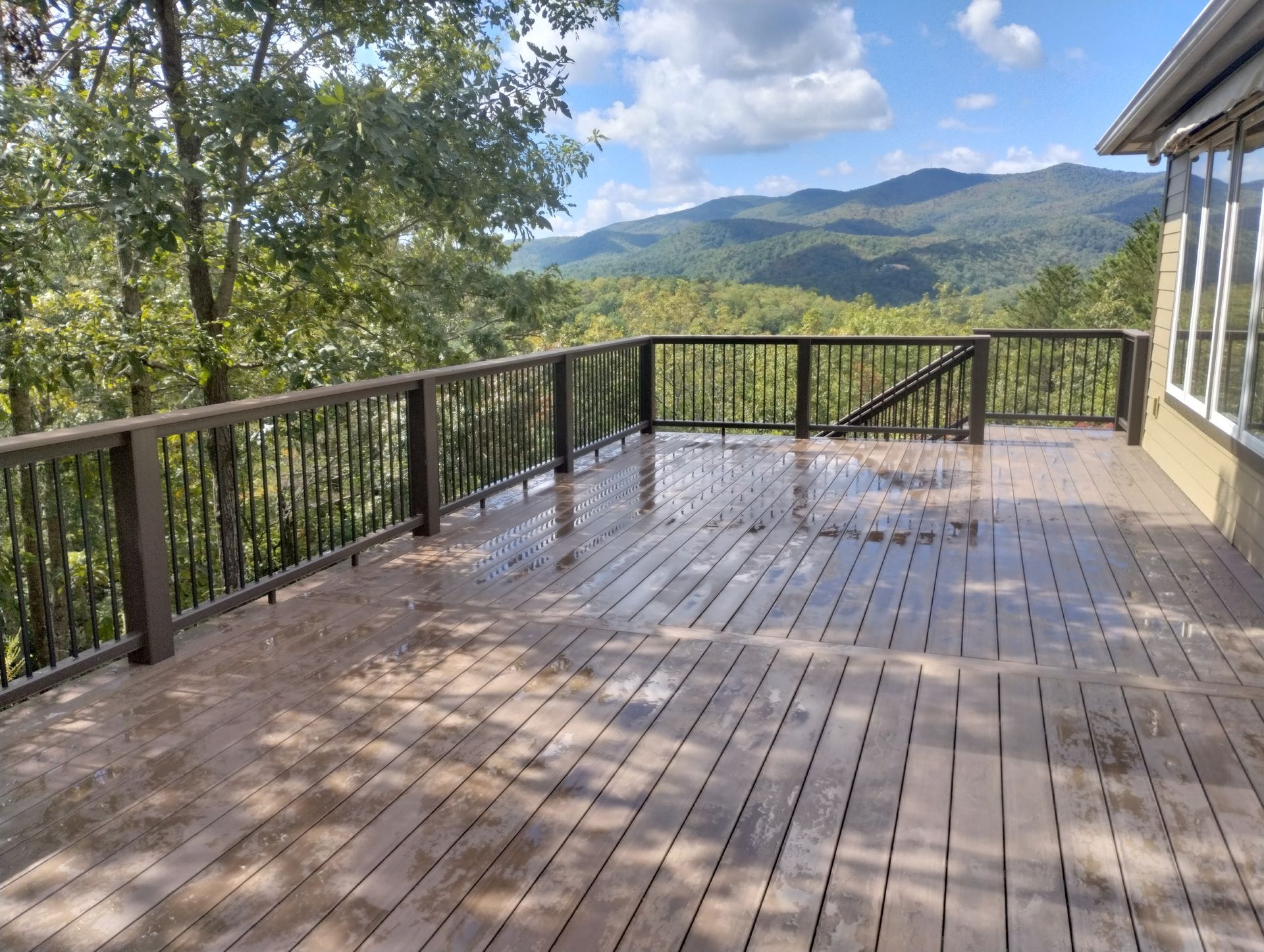 A large wooden deck with a view of mountains and trees.