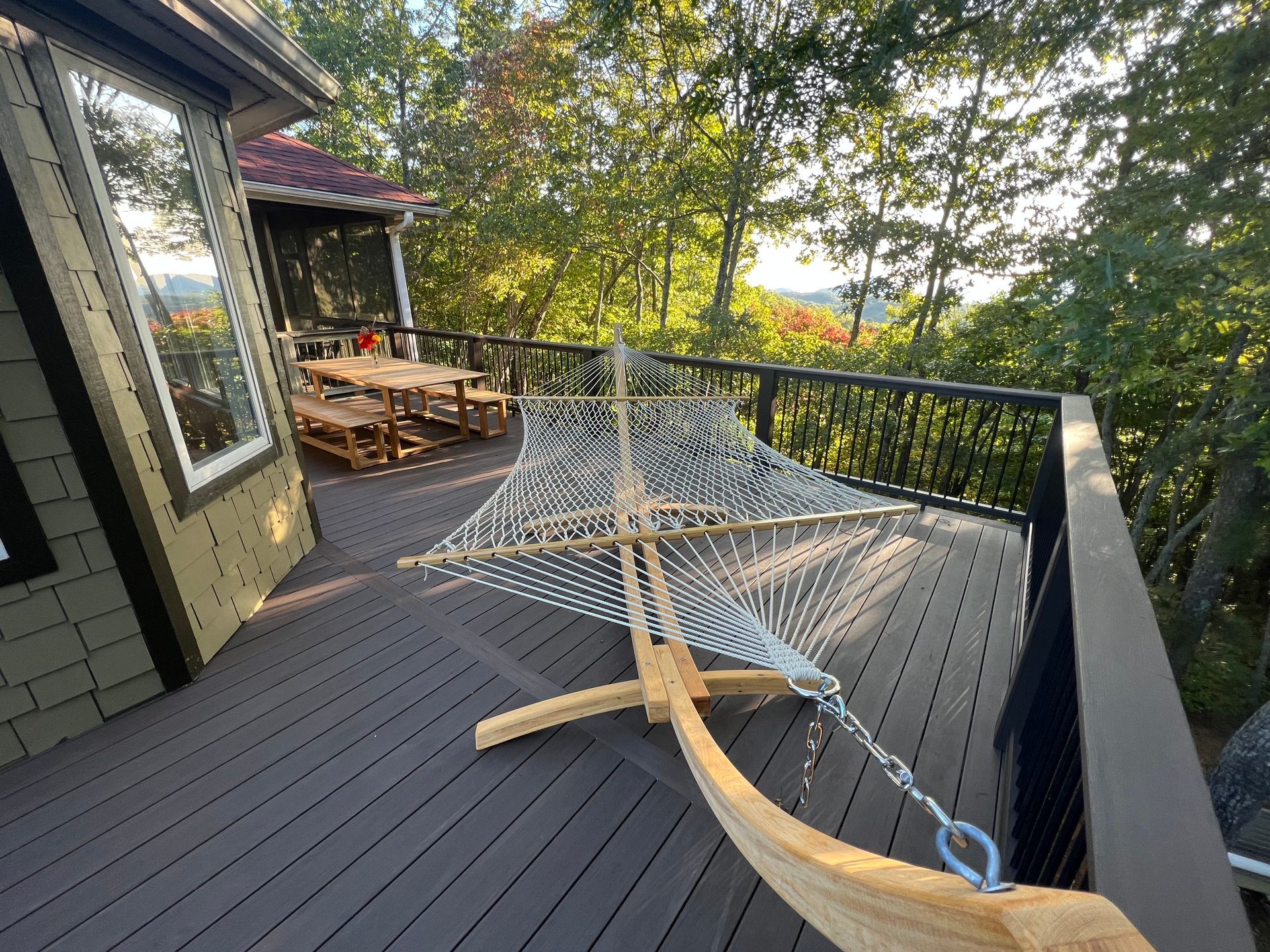 A hammock is sitting on a deck next to a house.