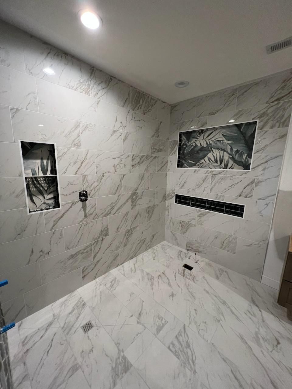A bathroom with marble tiles and a walk in shower.