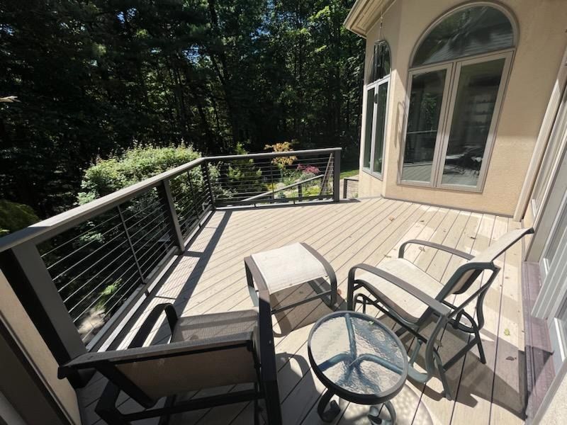 A deck with chairs and a table in front of a house