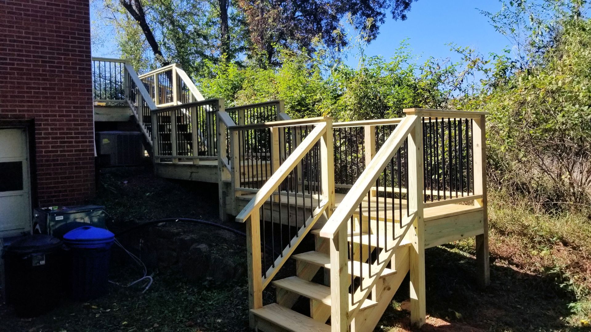 A wooden deck with stairs leading up to it and a brick building in the background.