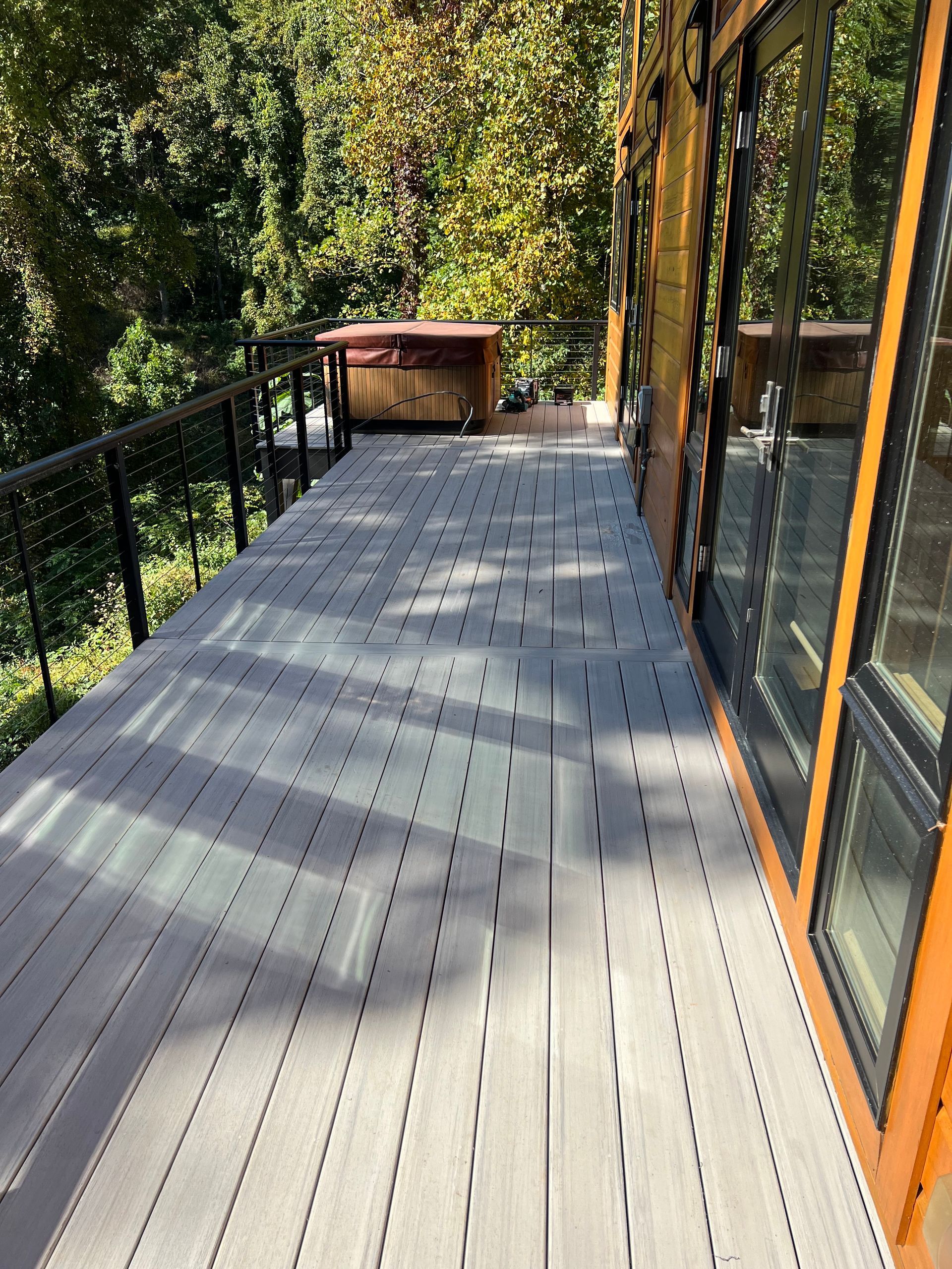 A large wooden deck with a hot tub in the background.