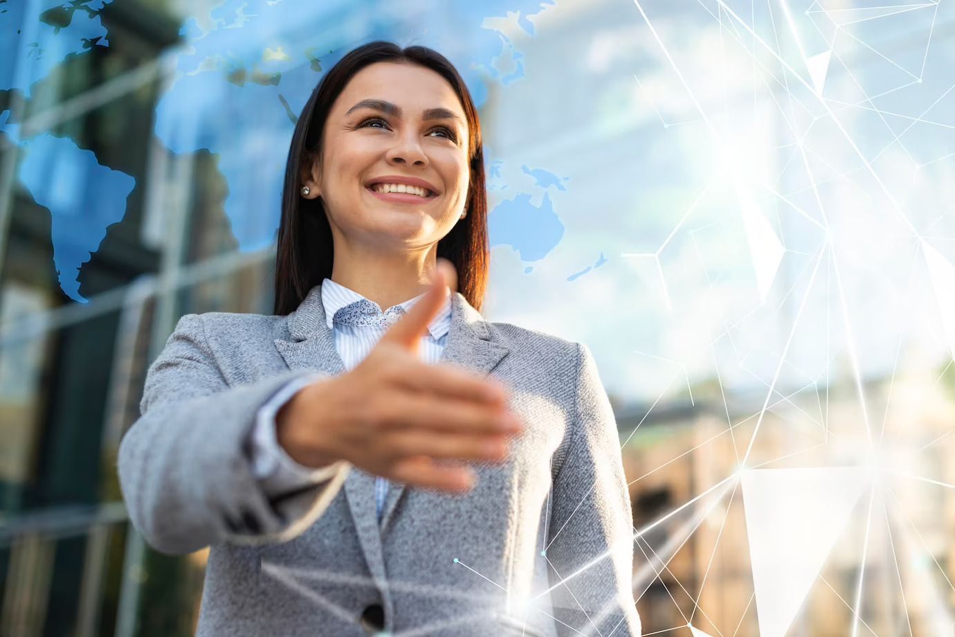 A woman in a suit is shaking hands with another woman in front of a map of the world.