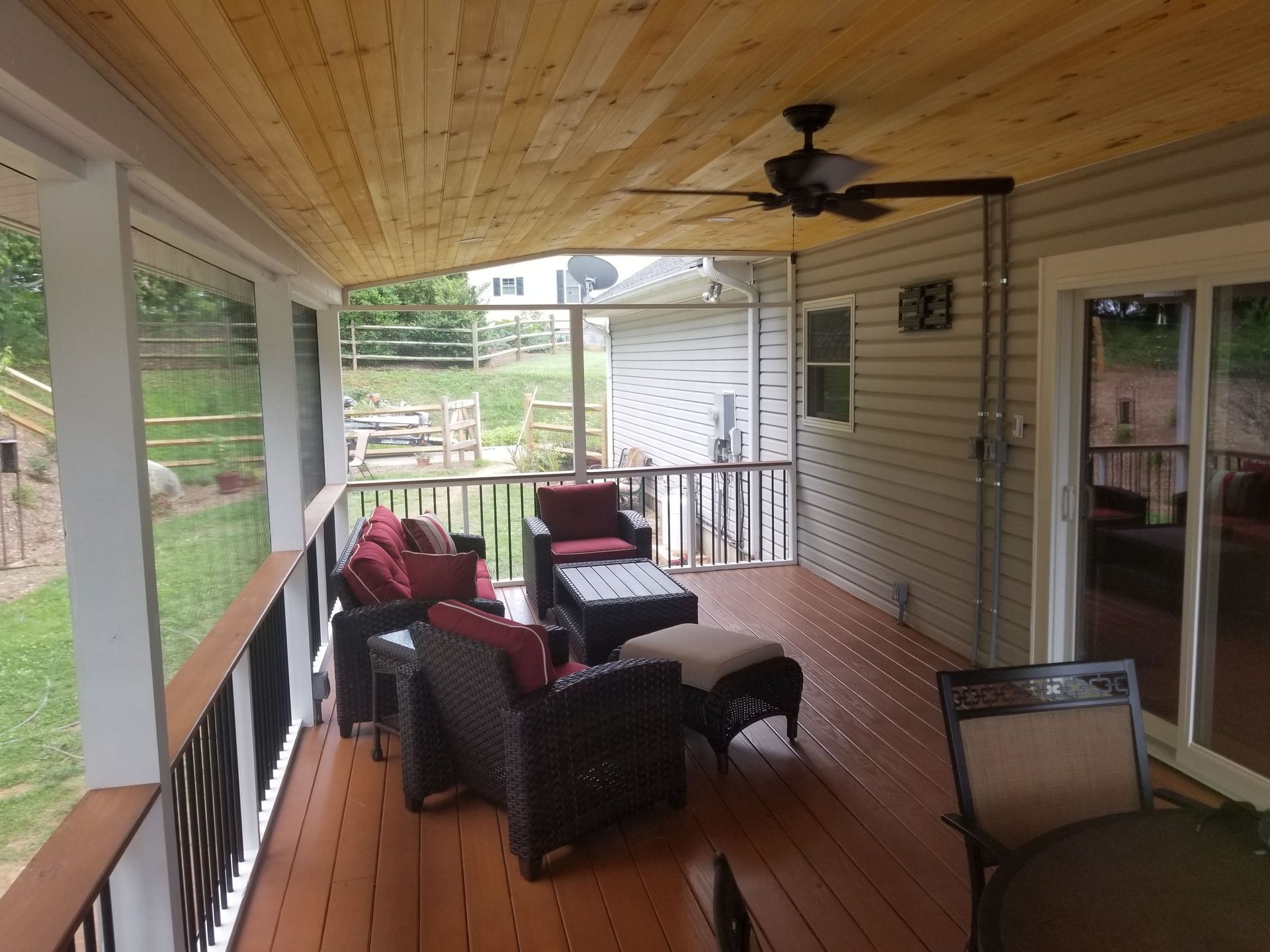 A screened in porch with furniture and a ceiling fan