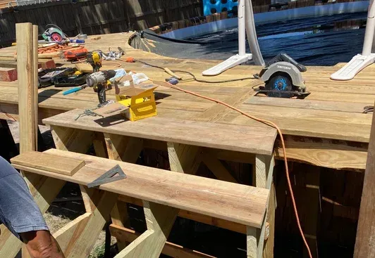 Ladder against a decaying tree trunk, tools attached, under a blue sky.