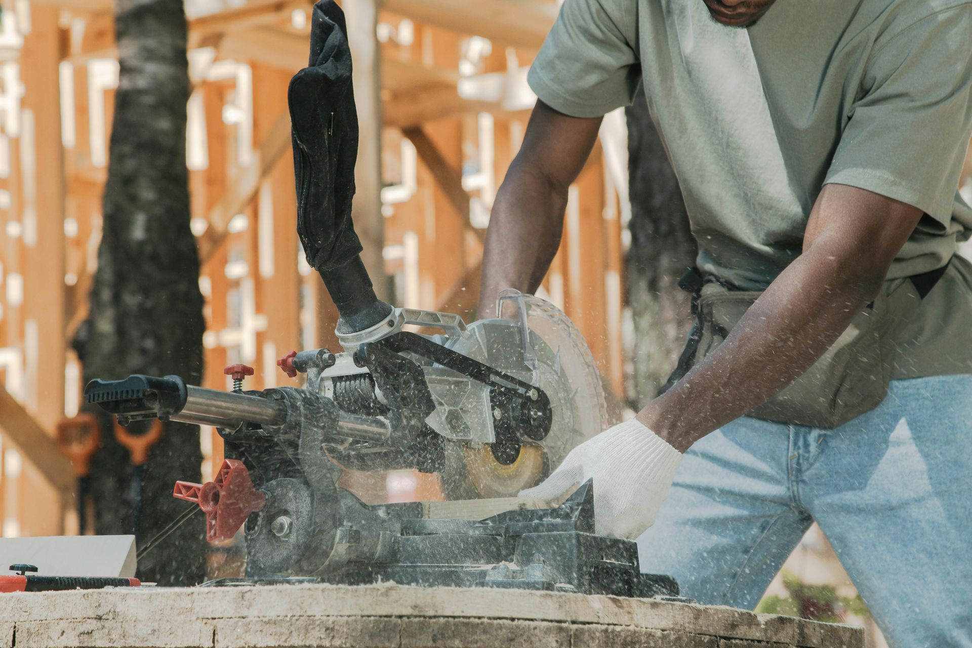 Man using a miter saw to cut wood at a construction site.