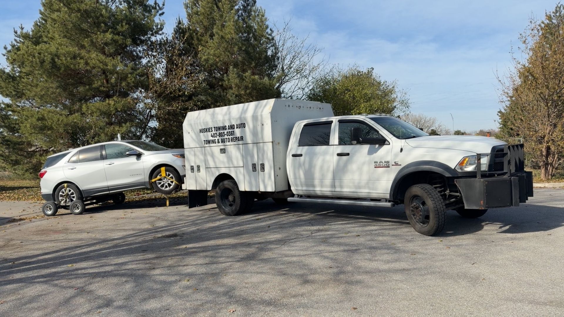 Huskies truck towing a trailer and a white SUV on a sunny day in Lincoln