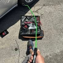 Person holding a green tool kit rod next to an open car lockout kit.