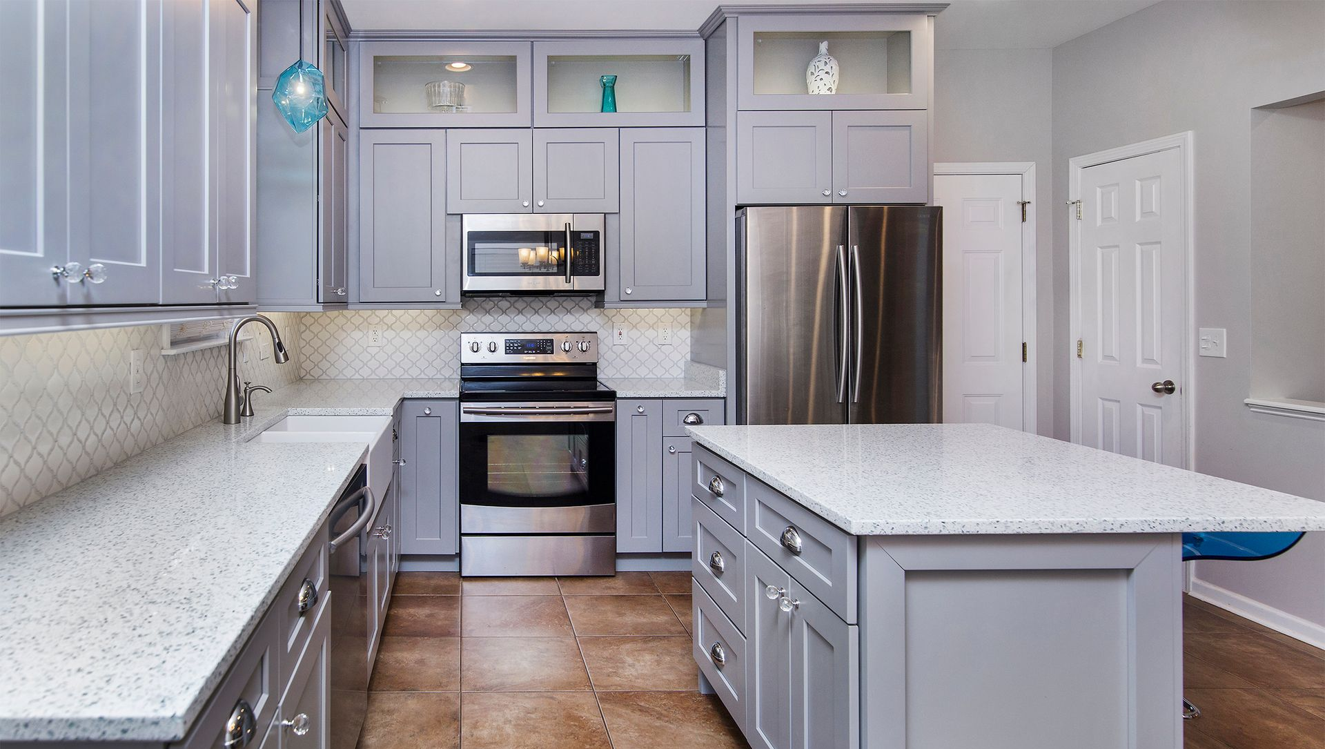 Modern gray kitchen with stainless steel appliances, white countertops, and an island.