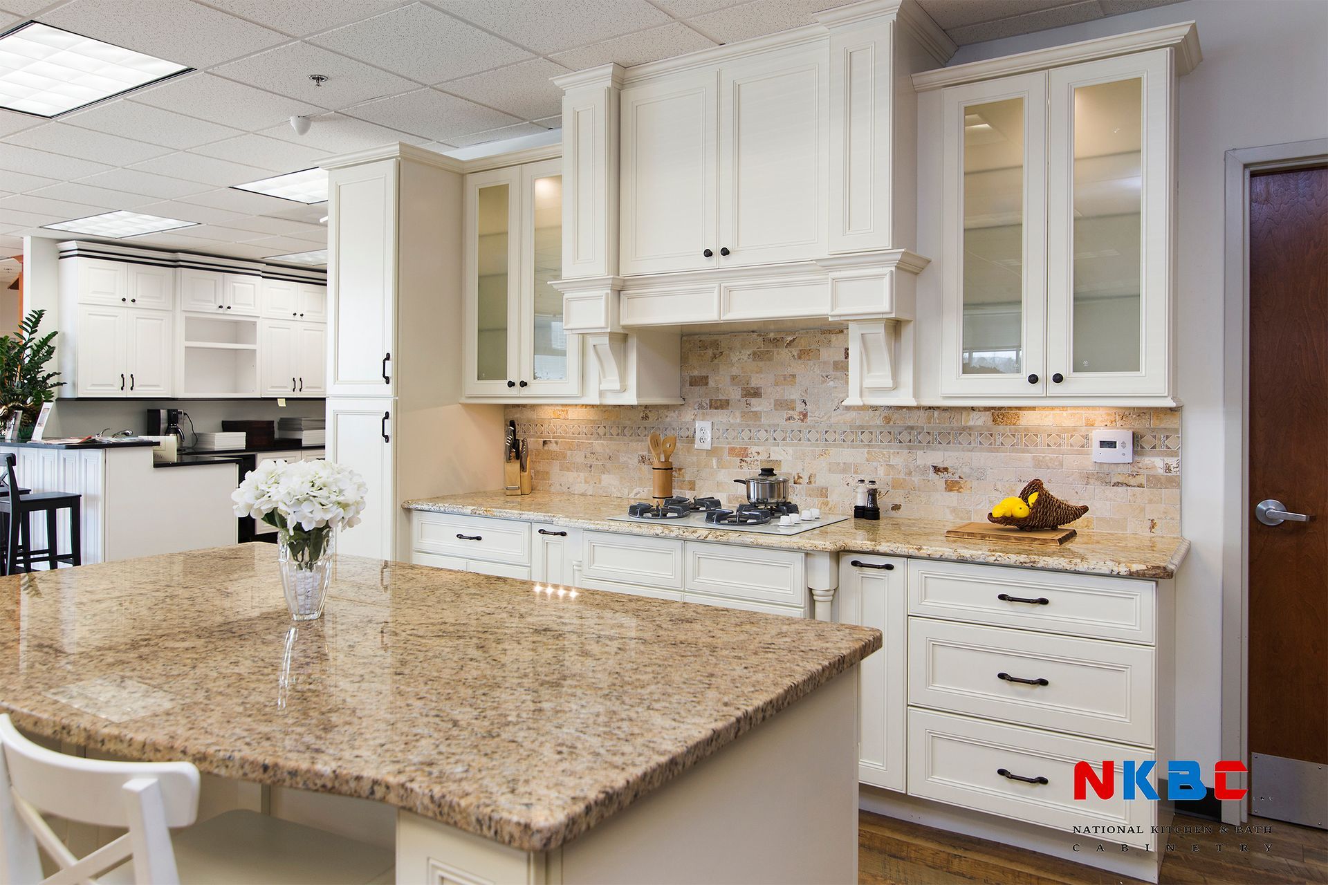 Cream-colored kitchen with granite countertops, cabinets, and a central island.