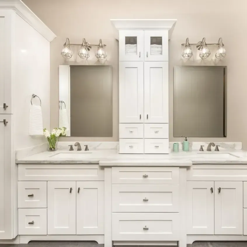 White bathroom vanity with two sinks, mirrors, and a center cabinet.