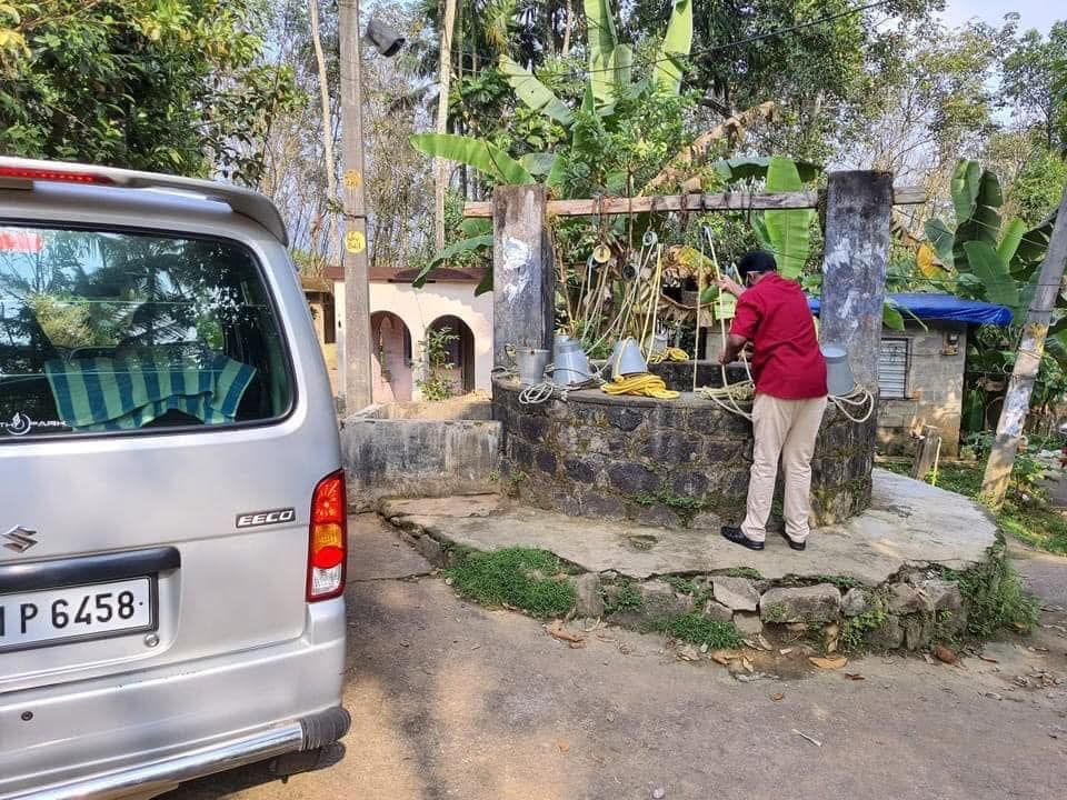 A man is standing next to a well next to a van.