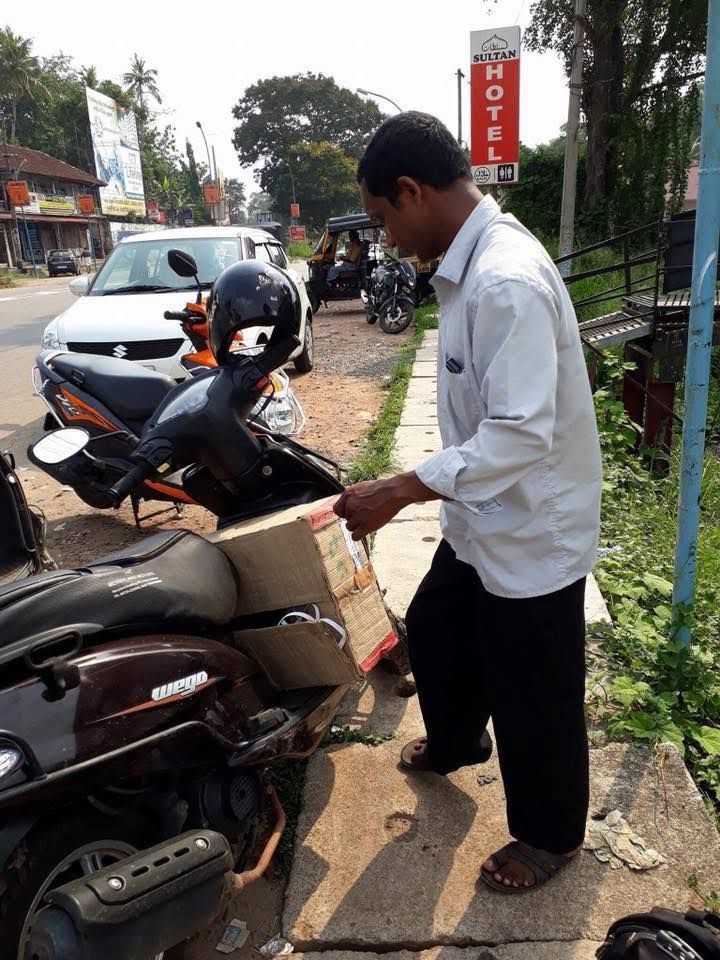 A man is working on a motorcycle with a hotel sign in the background