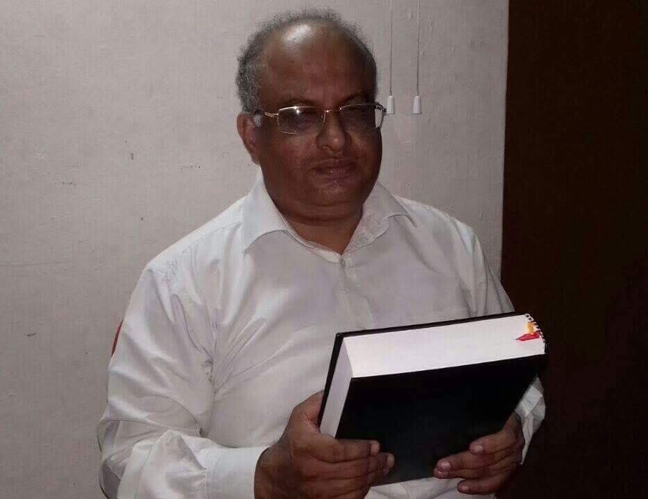 A man wearing glasses is holding a book in his hands.