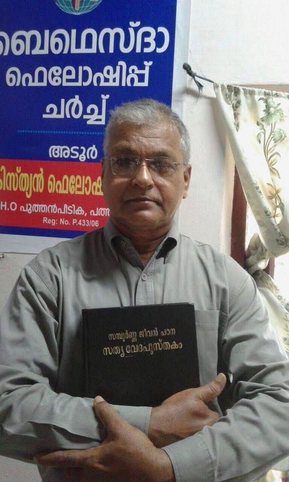 A man wearing glasses is holding a book in his hands.