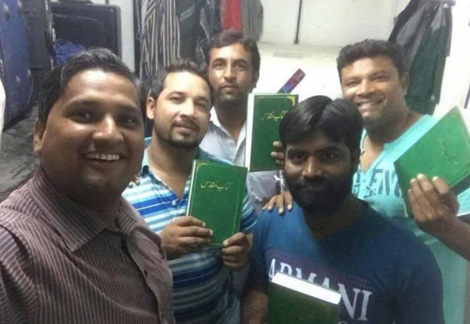 A group of men are posing for a picture while holding books.