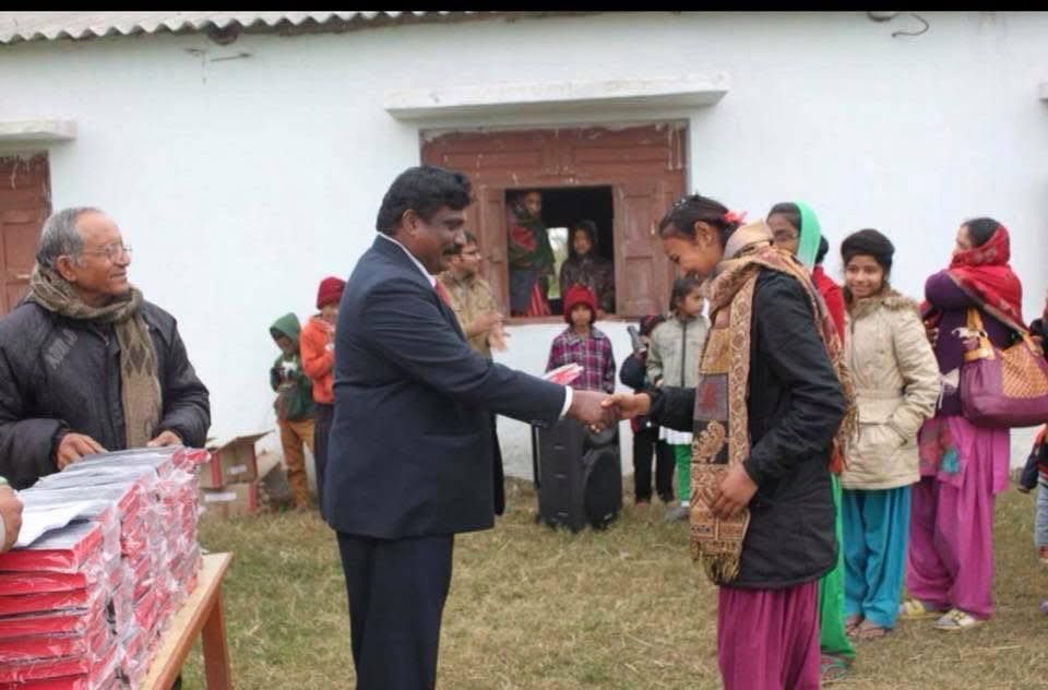 A man in a suit is shaking hands with a woman in front of a group of people.