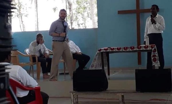 a man is giving a speech in front of a cross in a church