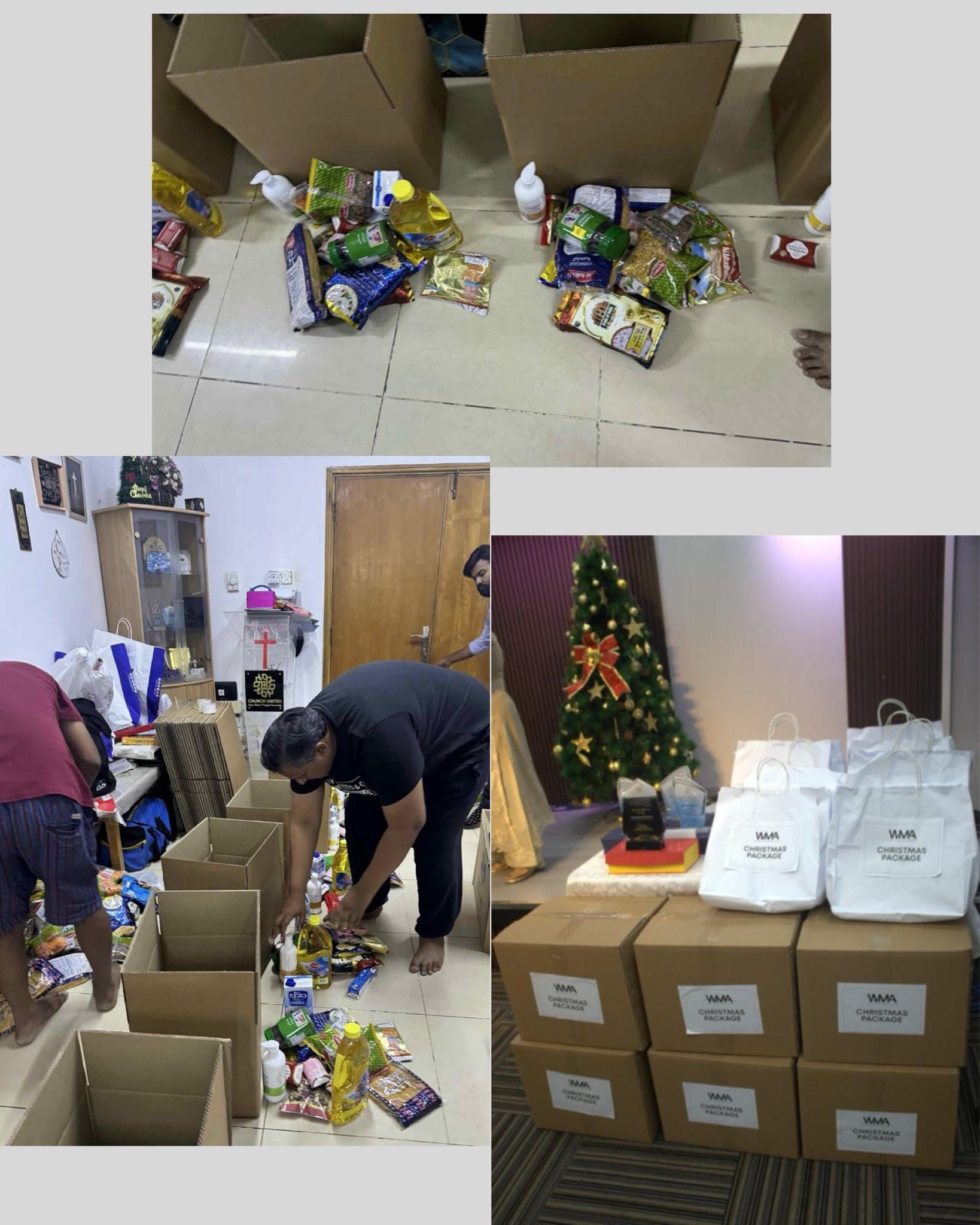 People packing food into boxes in a room, some are placing items while others prepare boxes. Christmas tree in background.