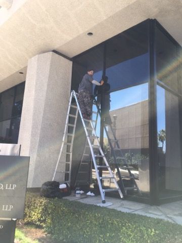 Worker on ladder cleaning windows of a building.