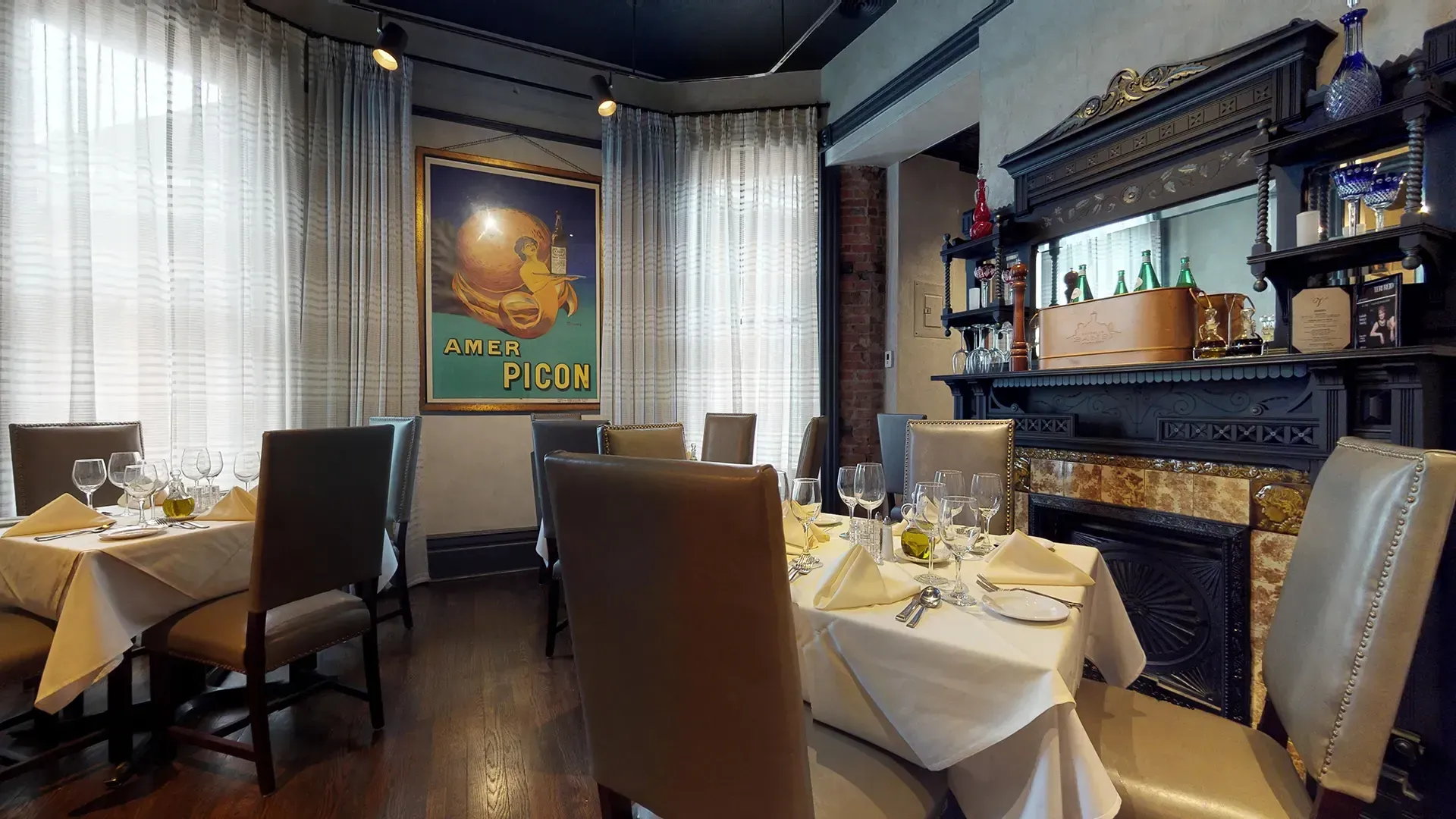 A dining room with tables and chairs and a fireplace.