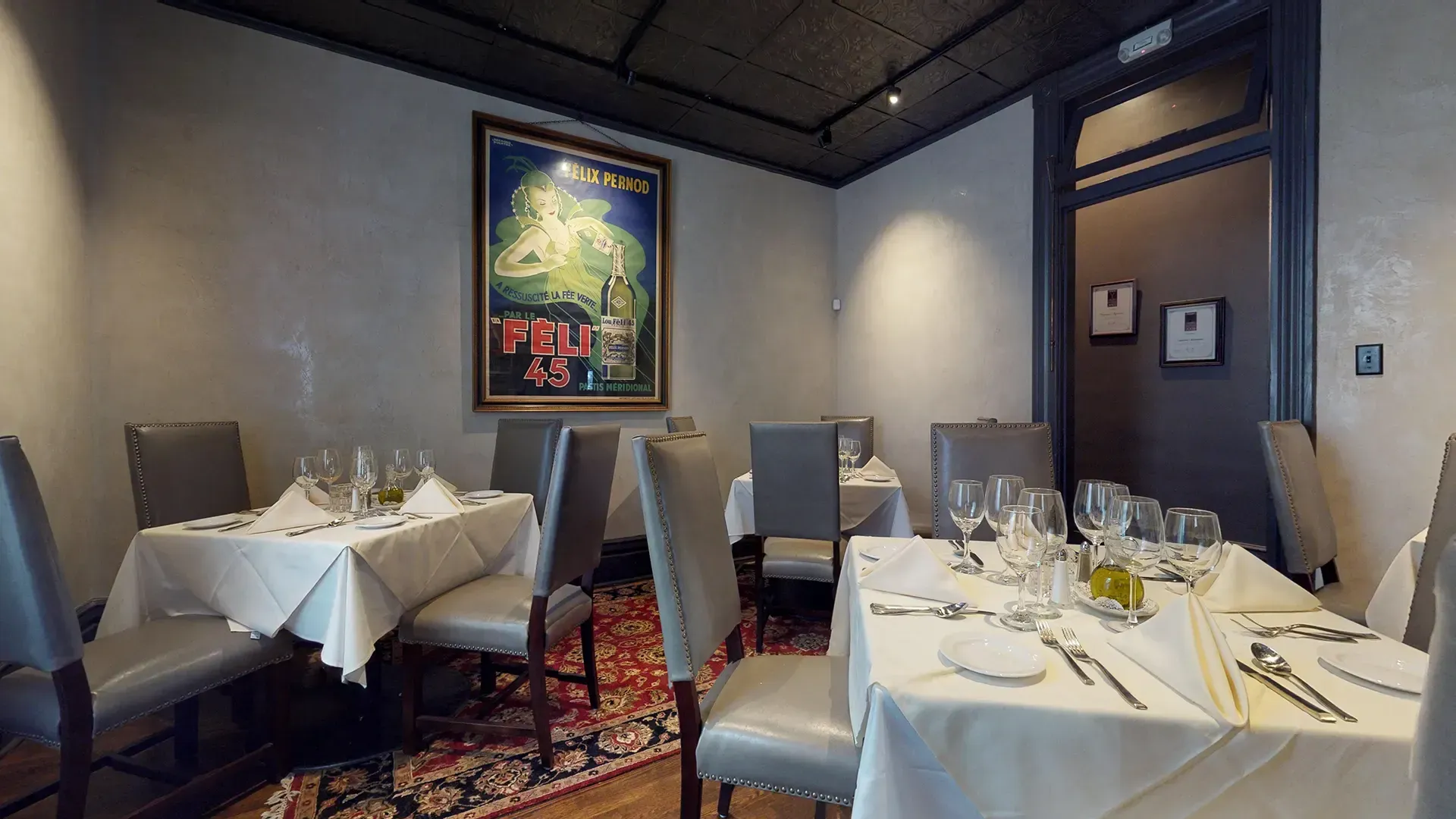 A dining room with tables and chairs and a painting on the wall.