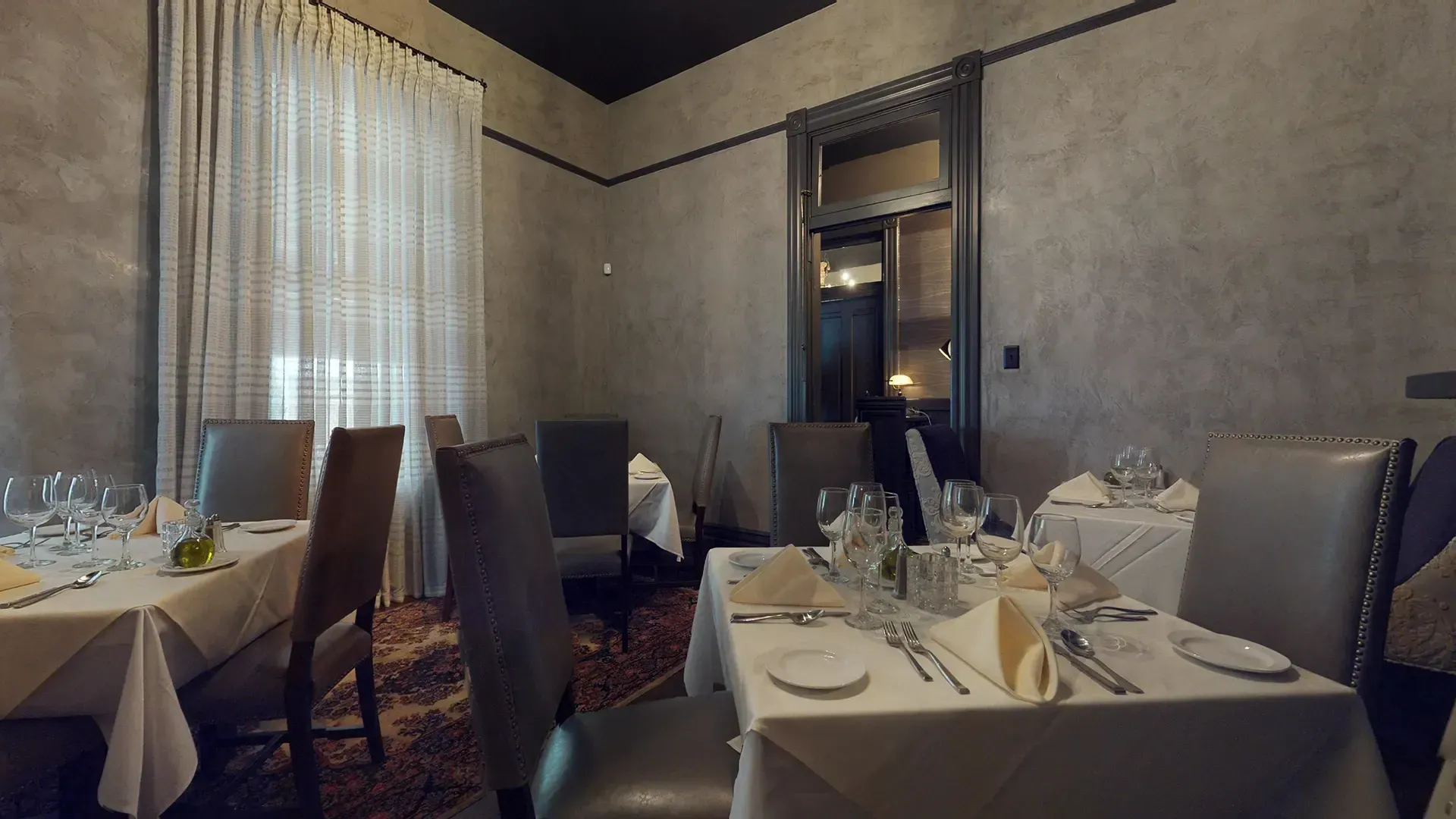 A dining room with tables and chairs set for a meal