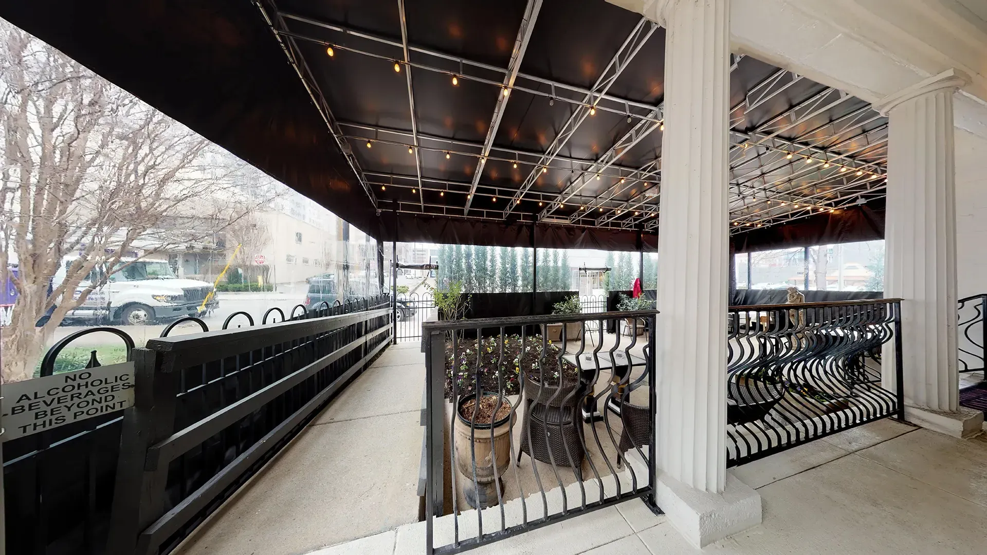 A balcony with a black awning and a wrought iron railing.