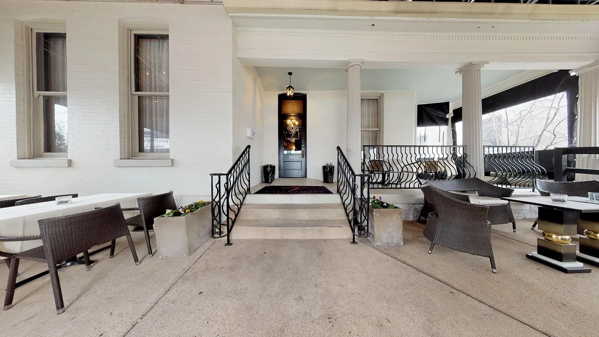 A large white house with a porch and stairs leading to the front door.